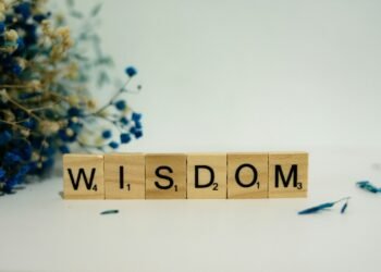 a wooden block spelling the word wisdom next to a bouquet of flowers