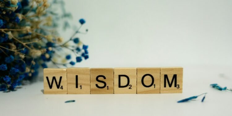 a wooden block spelling the word wisdom next to a bouquet of flowers