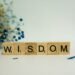 a wooden block spelling the word wisdom next to a bouquet of flowers